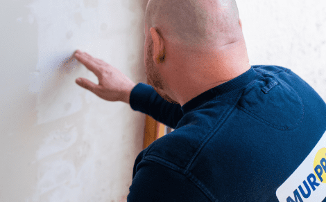 L’expert en humidité de Murprotec examine un mur humide.