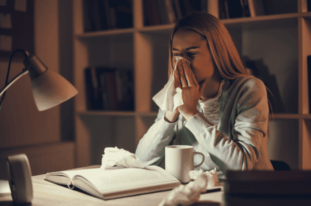 Vrouw zit aan bureau en is ziek