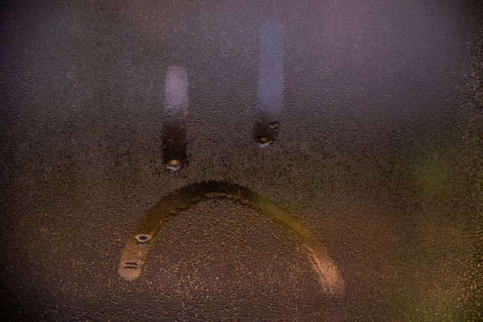 Condensation sur la fenêtre avec le dessin d’un smiley triste. 